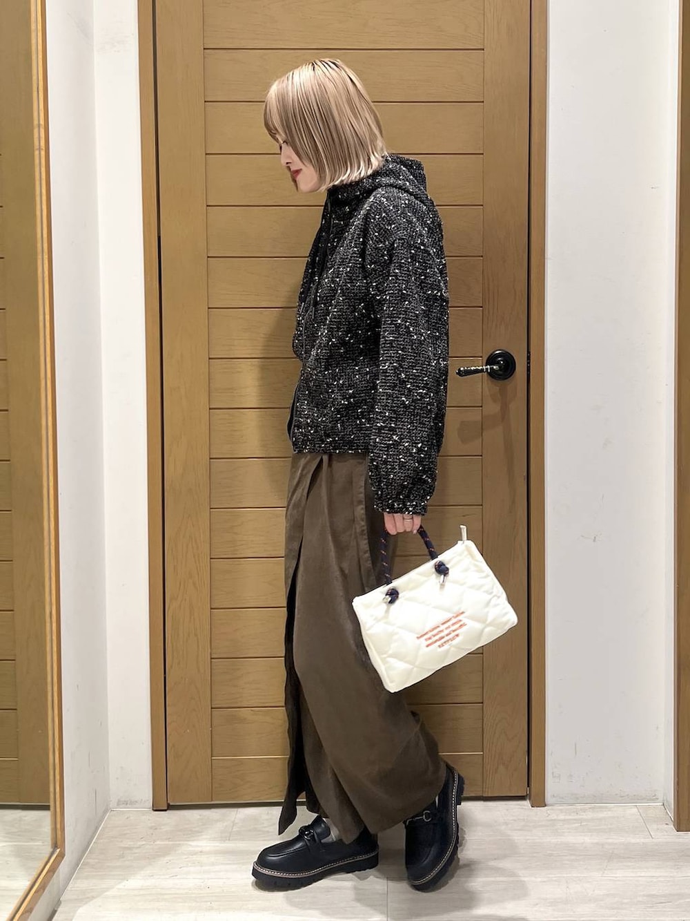 ブラック系のローファー、ブラック系のブルゾン、ホワイト系のショルダーバッグを着用したレディースの春コーディネートの3枚目の写真