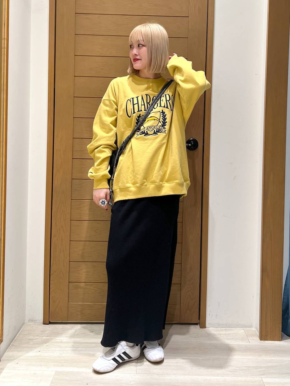 ブラック系のスカート、ブラック系のショルダーバッグ、イエロー系のスウェットを着用したレディースの冬コーディネートの5枚目の写真