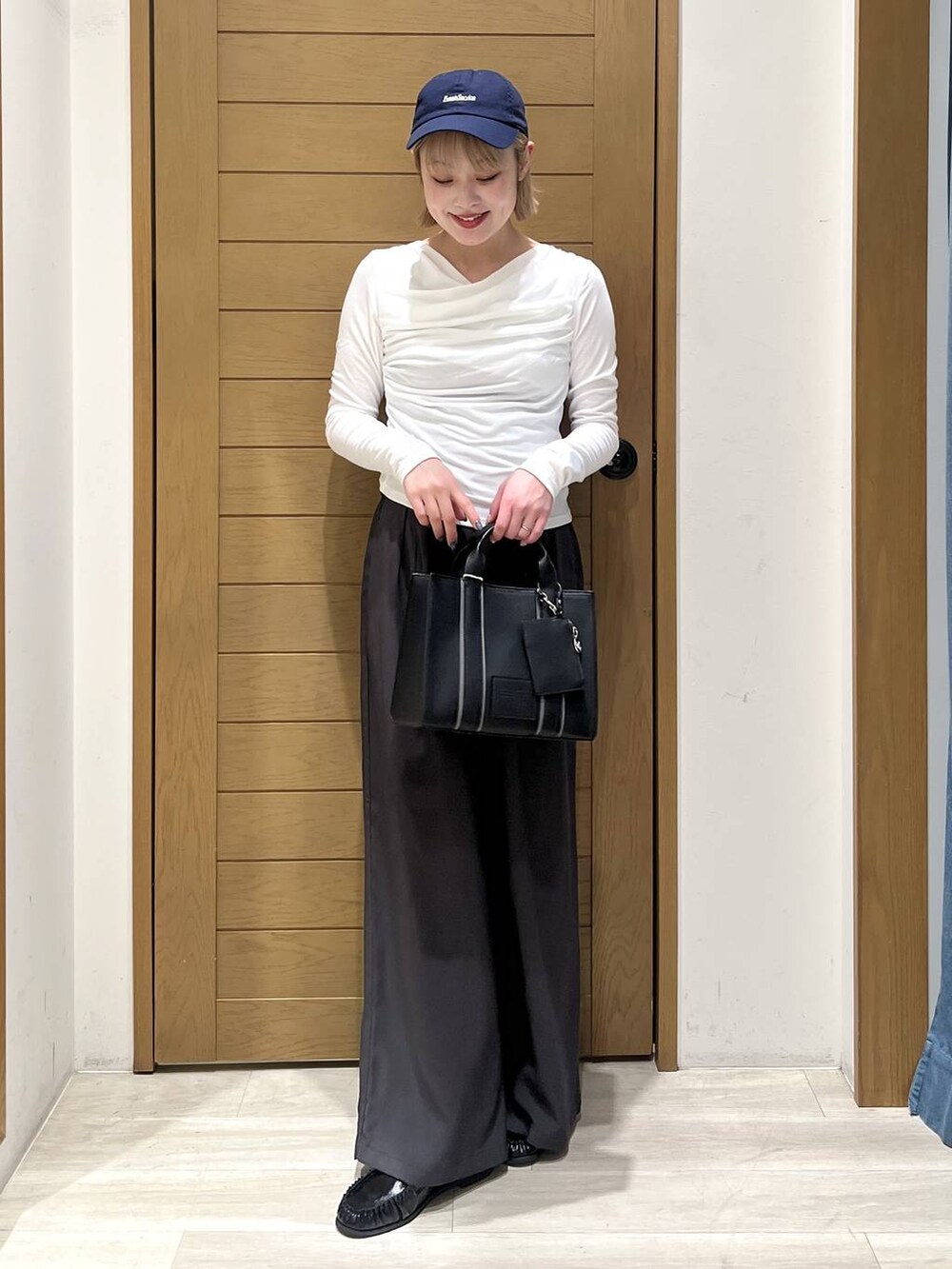 ブラック系のハンドバッグ、ブラック系のローファー、グレー系のその他パンツを着用したレディースの冬コーディネートの2枚目の写真