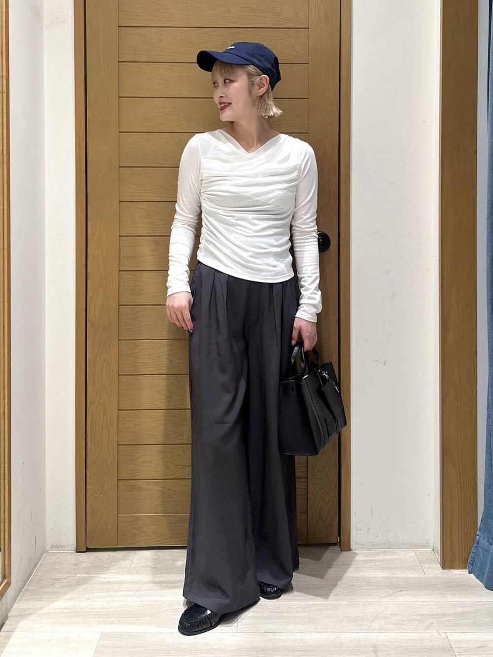 ブラック系のハンドバッグ、ブラック系のローファー、グレー系のその他パンツを着用したレディースの冬コーディネートの3枚目の写真