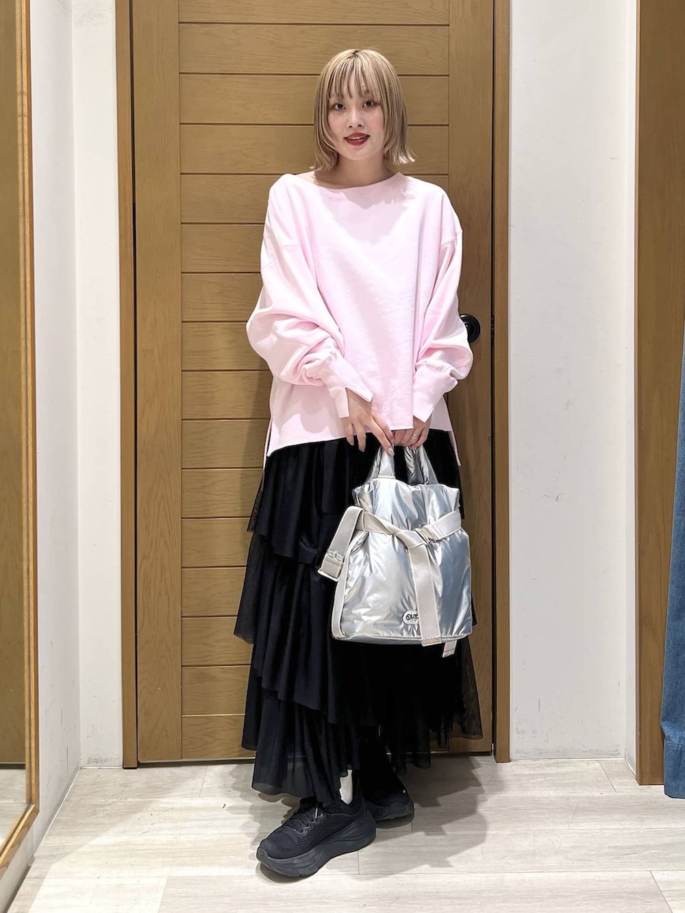 シルバー系のトートバッグ、ピンク系のスウェット、ブラック系のスカートを着用したレディースの春コーディネートの2枚目の写真