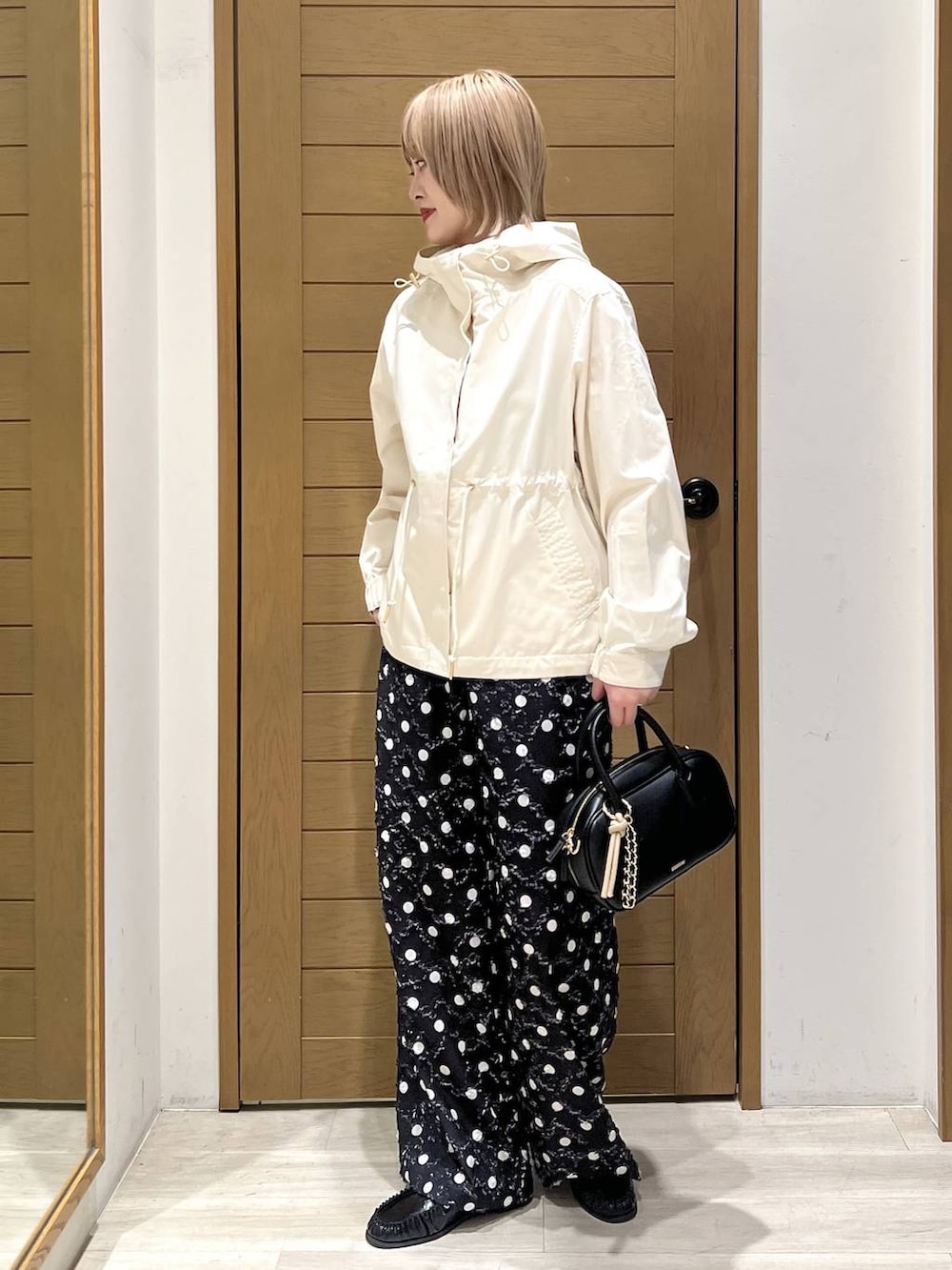 ホワイト系のマウンテンパーカー、ブラック系のローファー、ブラック系のハンドバッグを着用したレディースの春コーディネートの3枚目の写真