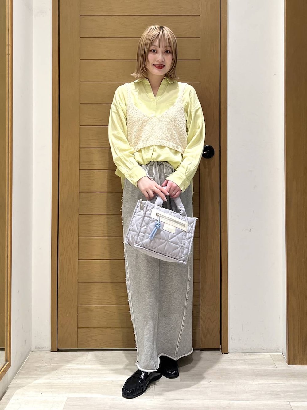 グレー系のショルダーバッグ、グレー系のスカート、ブラック系のローファーを着用したレディースの春コーディネートの5枚目の写真