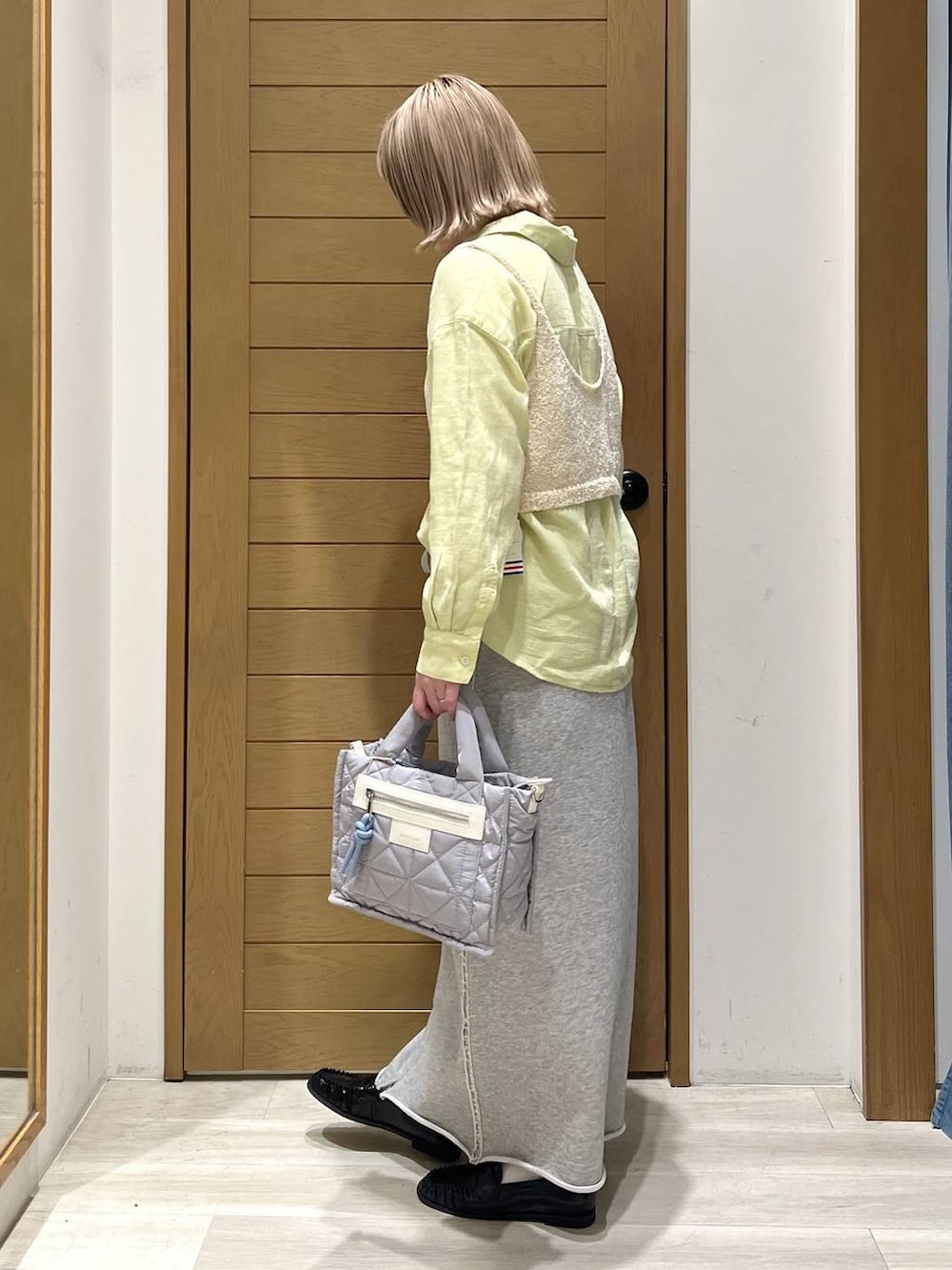 グレー系のショルダーバッグ、グレー系のスカート、ブラック系のローファーを着用したレディースの春コーディネートの3枚目の写真