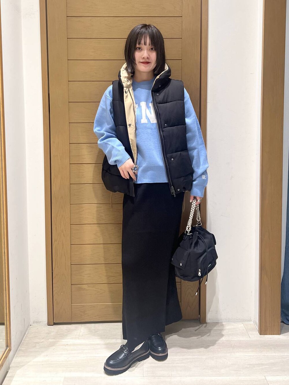 ブルー系のニット/セーター、ブラック系のローファー、ブラック系のハンドバッグを着用したレディースの秋コーディネートの6枚目の写真