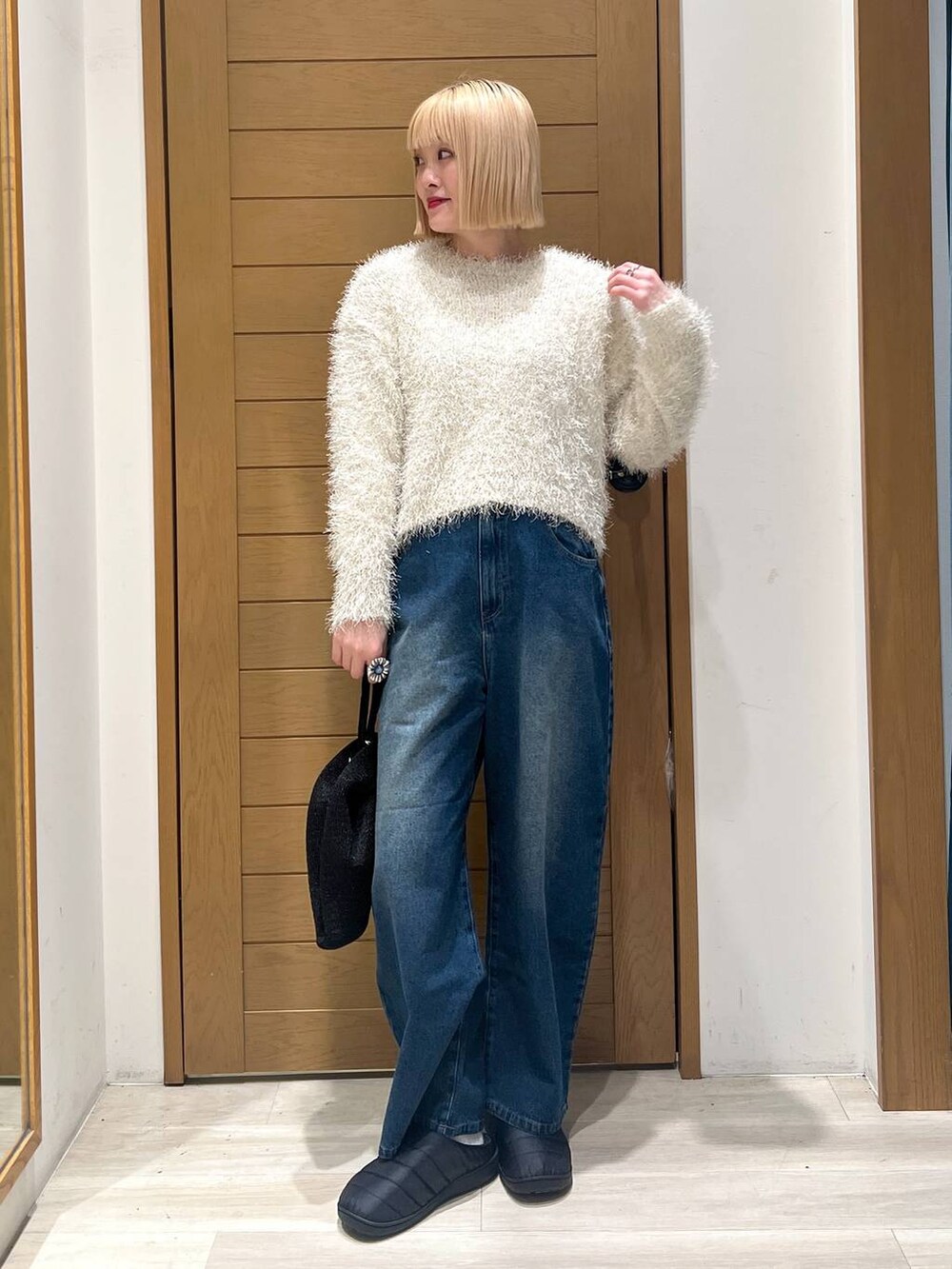 ホワイト系のニット/セーター、ブルー系のデニムパンツ、ブラック系のハンドバッグを着用したレディースの冬コーディネートの2枚目の写真