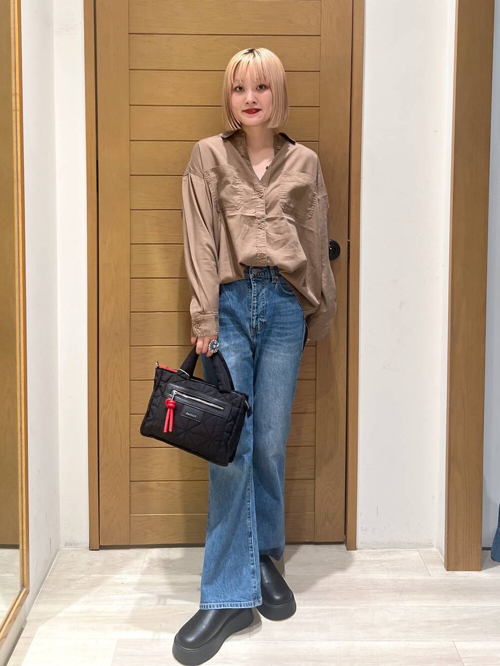 ブラック系のショルダーバッグ、ブラウン系のシャツ/ブラウス、ブルー系のデニムパンツを着用したレディースの夏コーディネートの3枚目の写真
