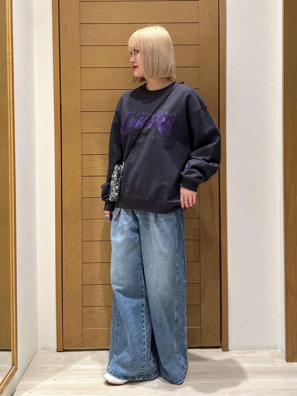 グレー系のショルダーバッグ、ブルー系のデニムパンツ、グレー系のスウェットを着用したレディースの冬コーディネートの2枚目の写真