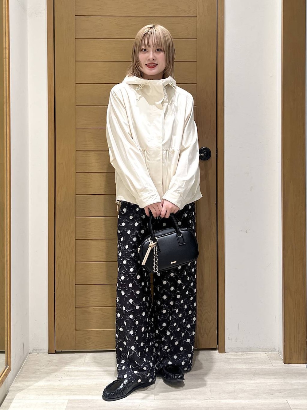 ホワイト系のマウンテンパーカー、ブラック系のローファー、ブラック系のハンドバッグを着用したレディースの春コーディネートの6枚目の写真