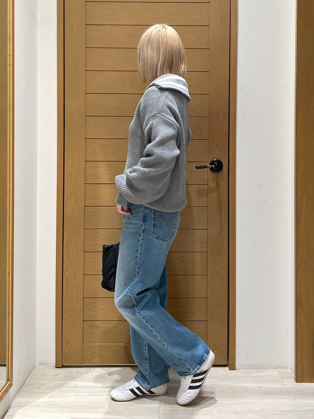 ブルー系のデニムパンツ、ブラック系のトートバッグ、グレー系のニット/セーターを着用したレディースの冬コーディネートの3枚目の写真