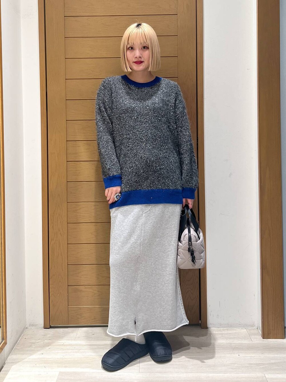 グレー系のニット/セーター、ベージュ系のハンドバッグ、グレー系のスカートを着用したレディースの冬コーディネートの6枚目の写真