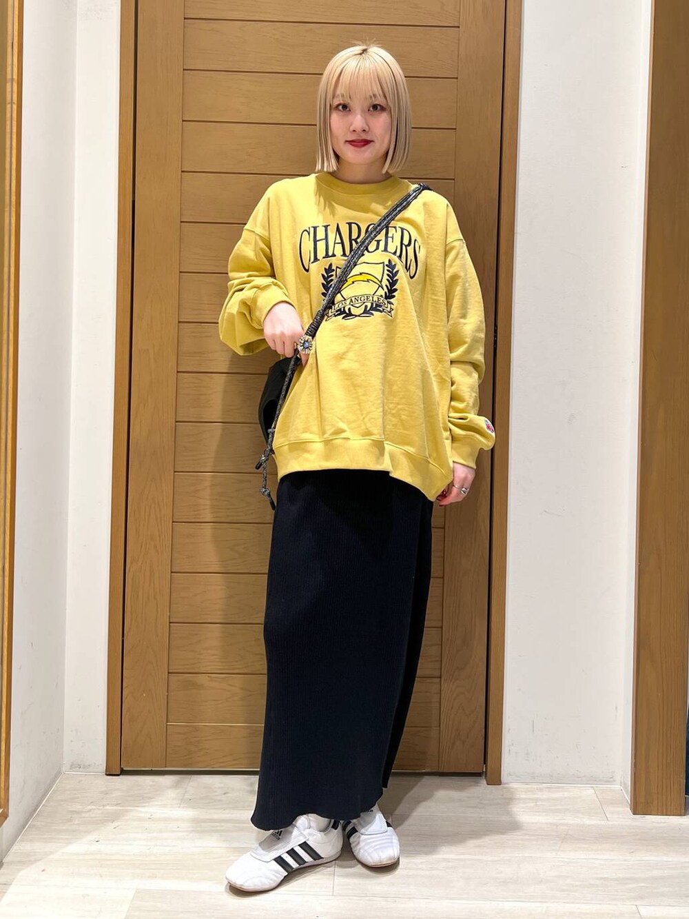 ブラック系のスカート、ブラック系のショルダーバッグ、イエロー系のスウェットを着用したレディースの冬コーディネートの2枚目の写真