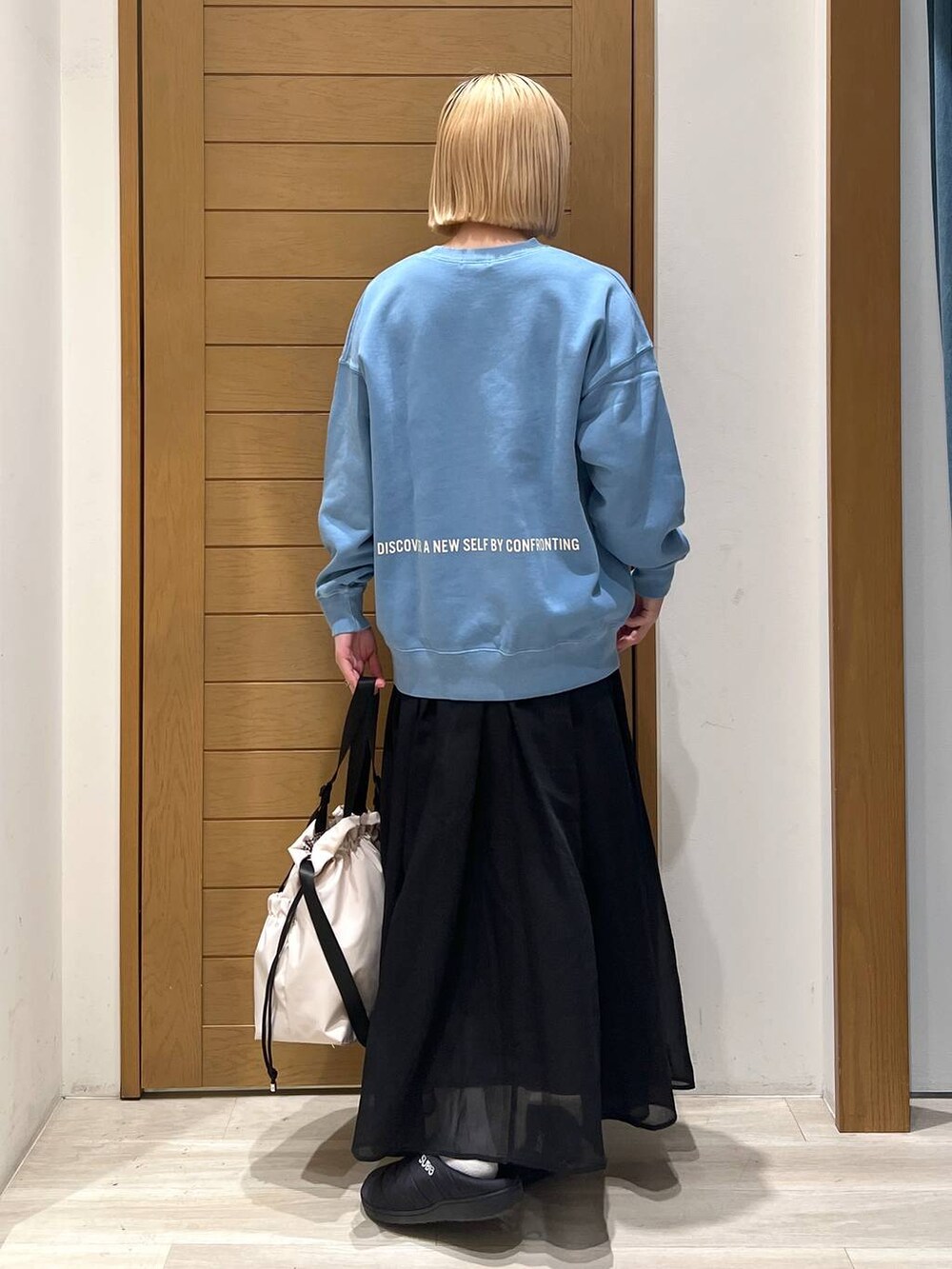 ブルー系のスウェット、ブラック系のスカート、ホワイト系のトートバッグを着用したレディースの冬コーディネートの4枚目の写真