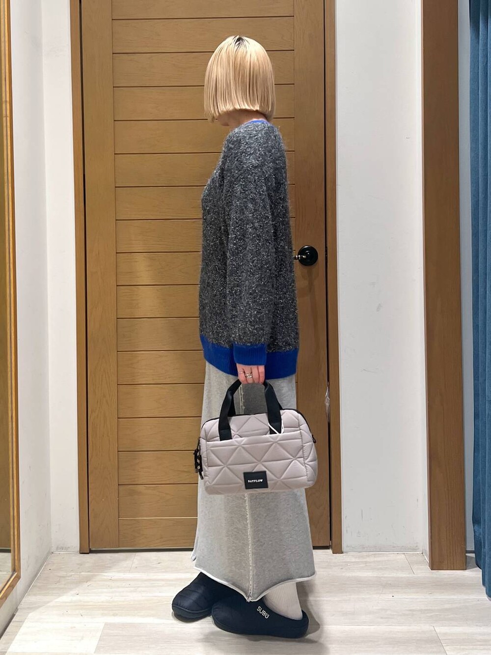 グレー系のニット/セーター、ベージュ系のハンドバッグ、グレー系のスカートを着用したレディースの冬コーディネートの4枚目の写真