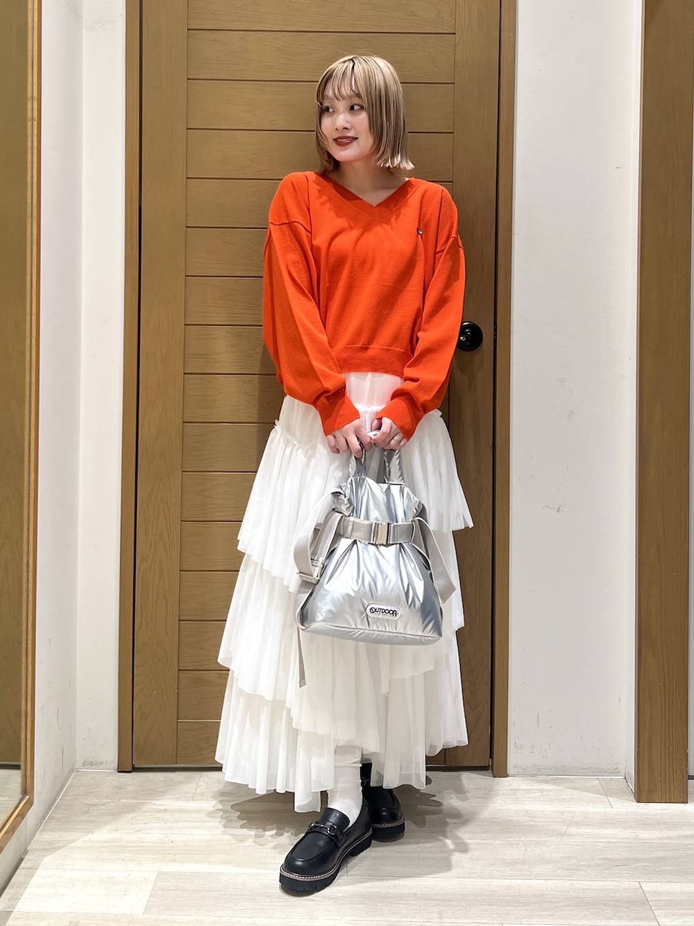 シルバー系のトートバッグ、ブラック系のローファー、オレンジ系のニット/セーターを着用したレディースの春コーディネートの5枚目の写真
