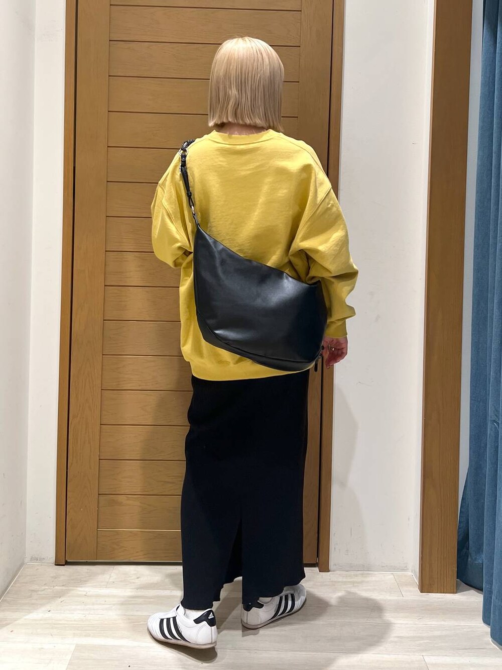 ブラック系のスカート、ブラック系のショルダーバッグ、イエロー系のスウェットを着用したレディースの冬コーディネートの3枚目の写真