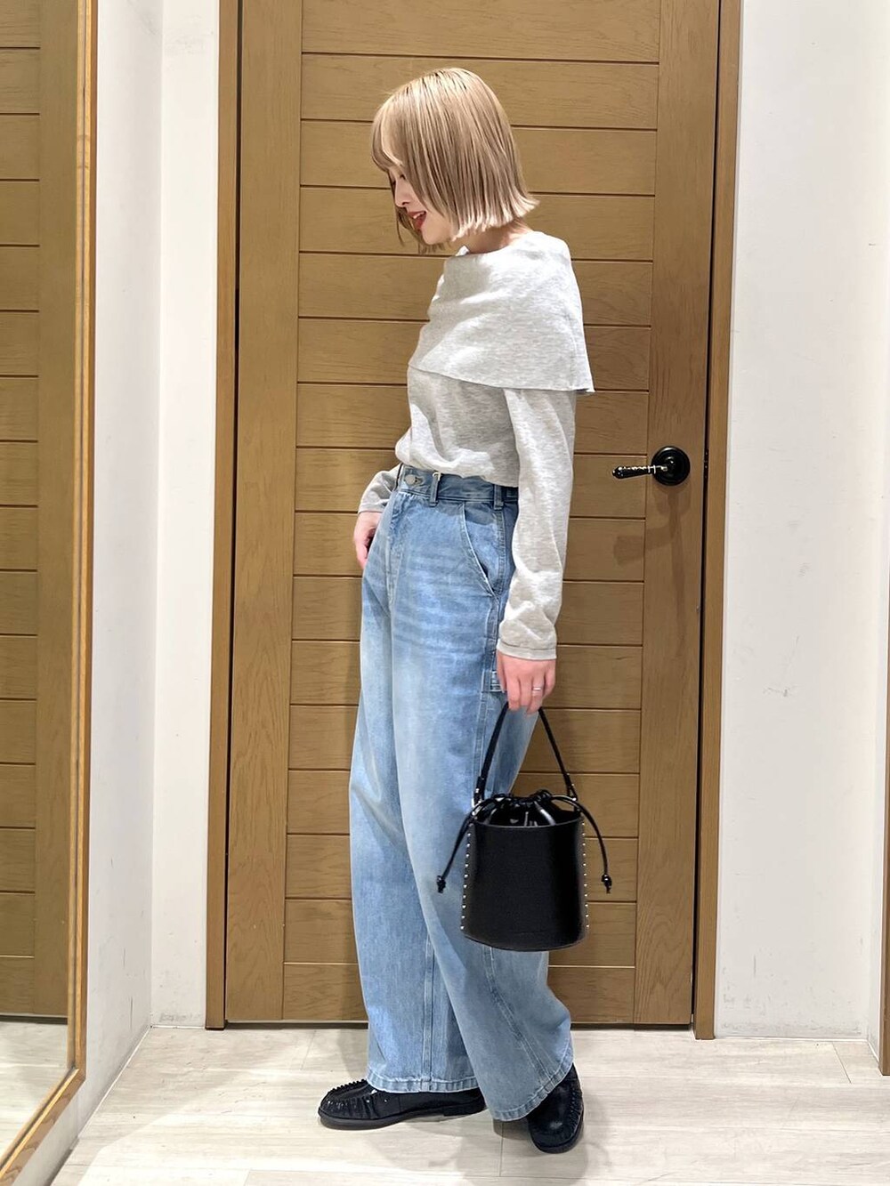 ブラック系のハンドバッグ、ブルー系のデニムパンツ、ブラック系のローファーを着用したレディースの春コーディネートの3枚目の写真