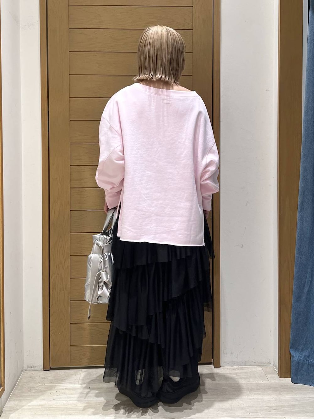 シルバー系のトートバッグ、ピンク系のスウェット、ブラック系のスカートを着用したレディースの春コーディネートの7枚目の写真