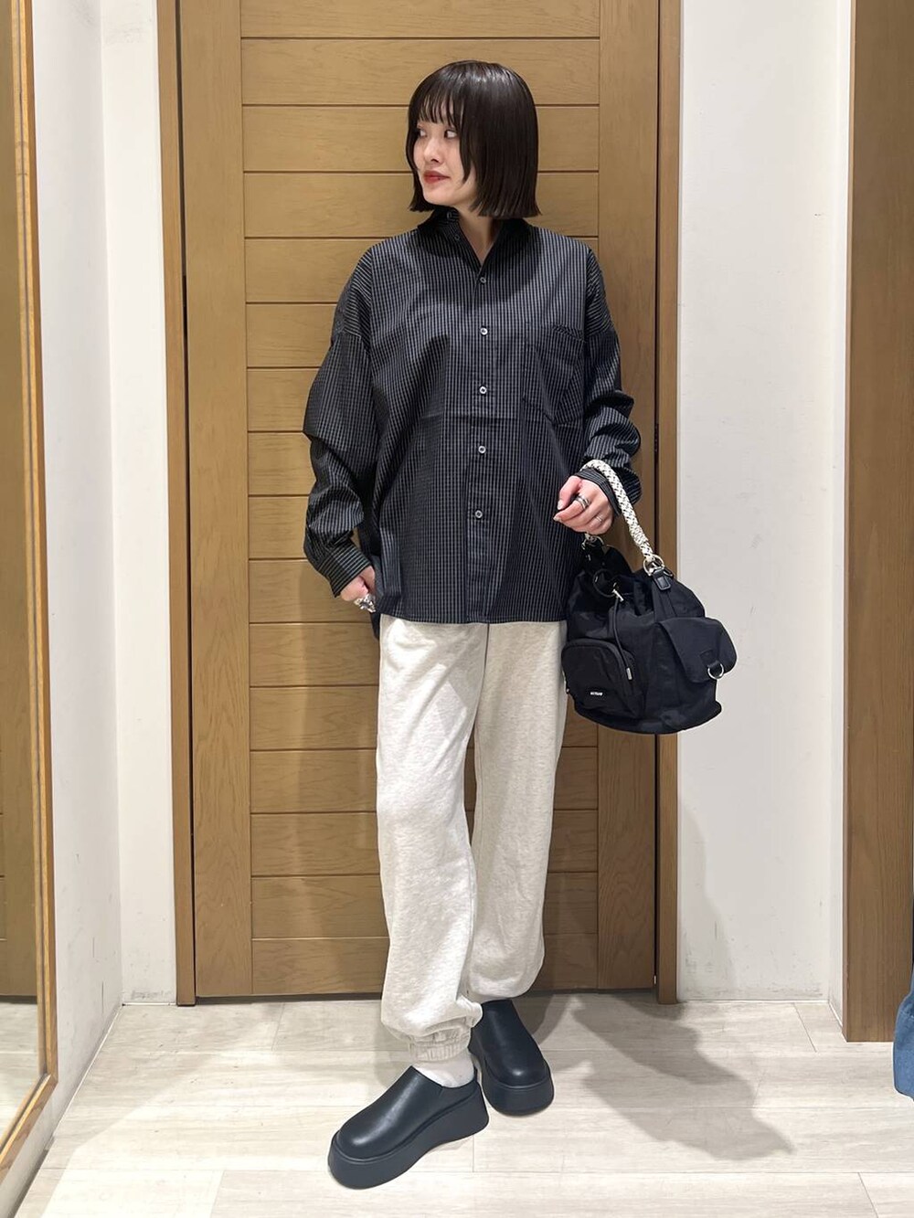 ベージュ系のスウェットパンツ、ブラック系のサンダル、ブラック系のハンドバッグを着用したレディースの秋コーディネートの2枚目の写真