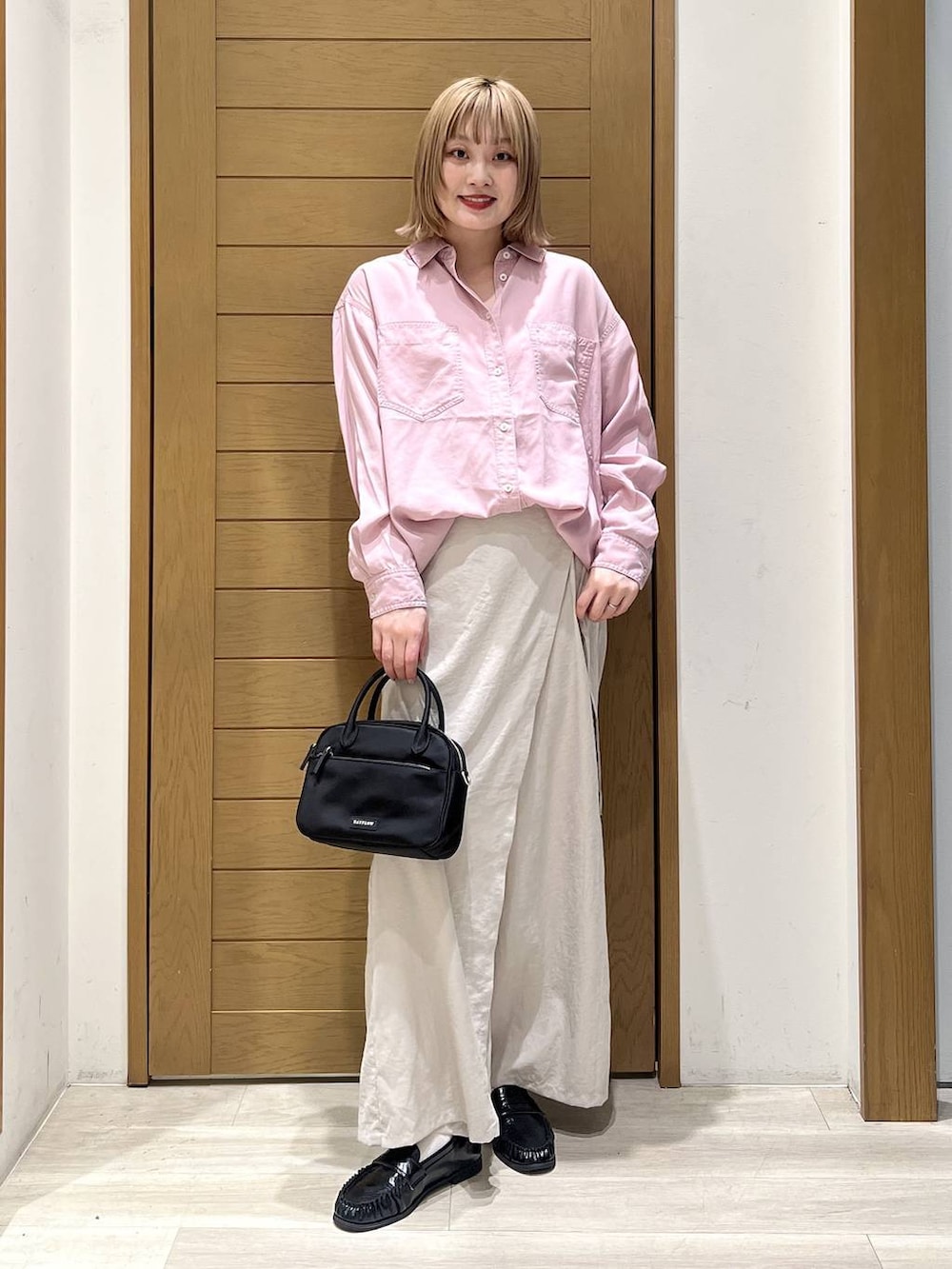 ピンク系のシャツ/ブラウス、ブラック系のハンドバッグ、ブラック系のローファーを着用したレディースの春コーディネートの6枚目の写真