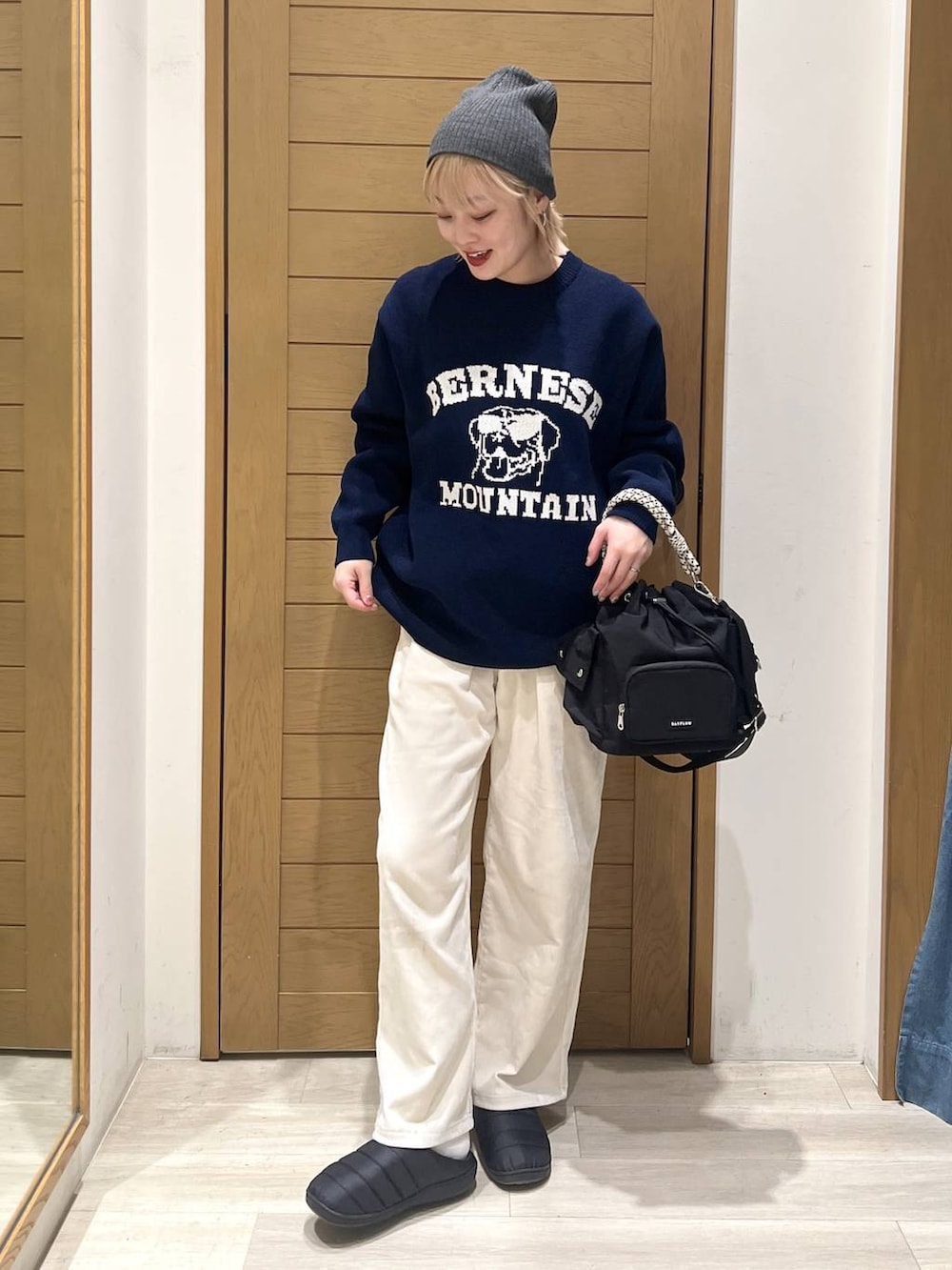 ブラック系のハンドバッグ、ホワイト系のその他パンツ、ブルー系のニット/セーターを着用したレディースの冬コーディネートの3枚目の写真