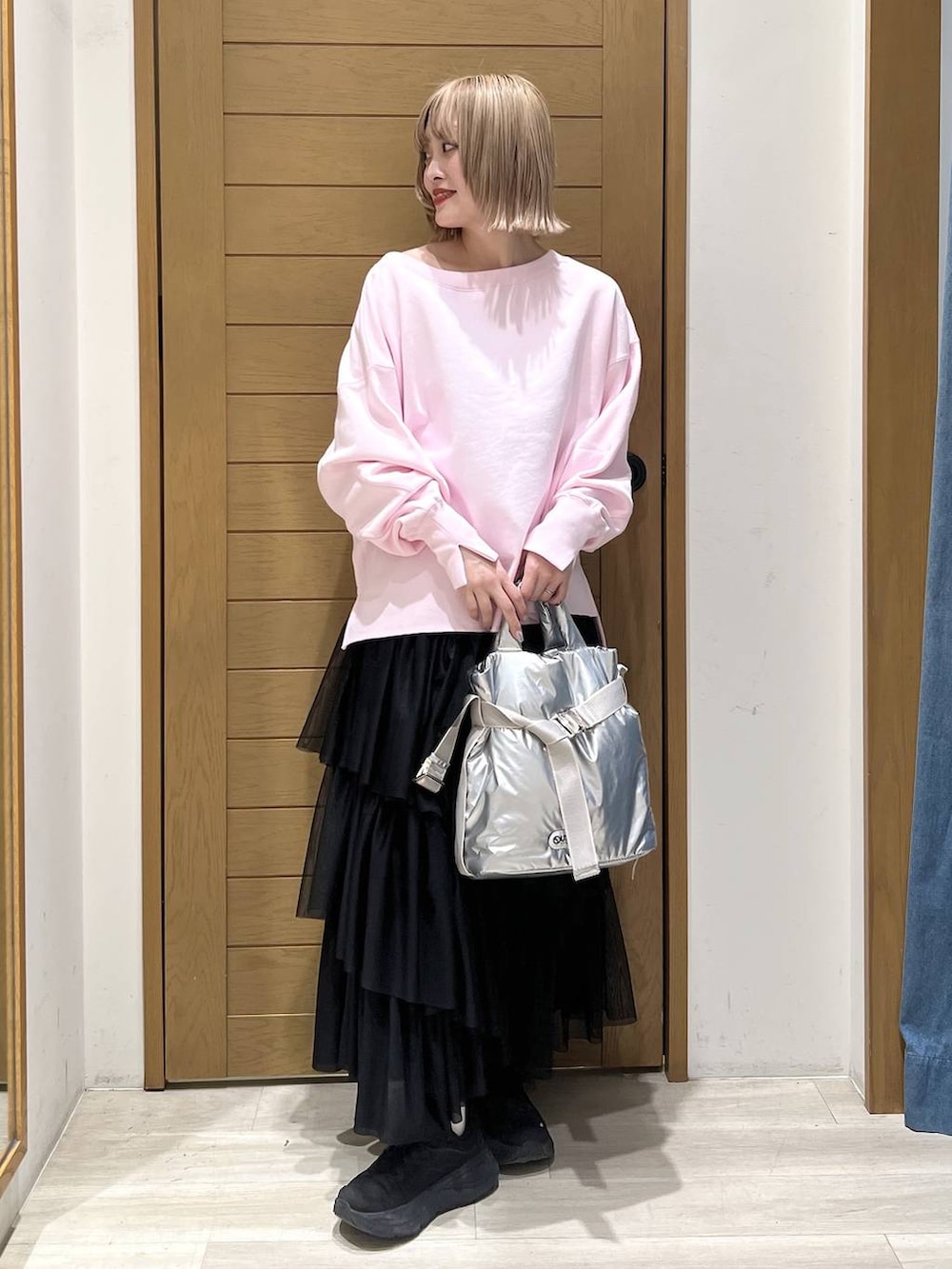 シルバー系のトートバッグ、ピンク系のスウェット、ブラック系のスカートを着用したレディースの春コーディネートの4枚目の写真