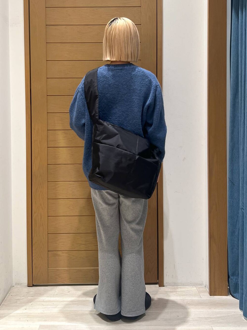 グレー系のスウェットパンツ、ブルー系のニット/セーター、ブラック系のショルダーバッグを着用したレディースの冬コーディネートの3枚目の写真