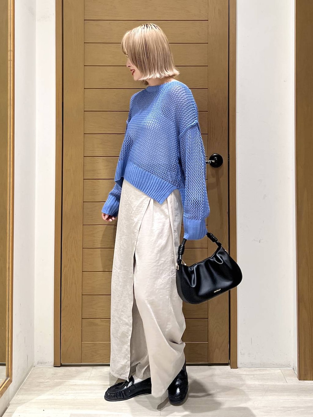 ブラック系のハンドバッグ、ブラック系のローファー、ブルー系のニット/セーターを着用したレディースの春コーディネートの3枚目の写真