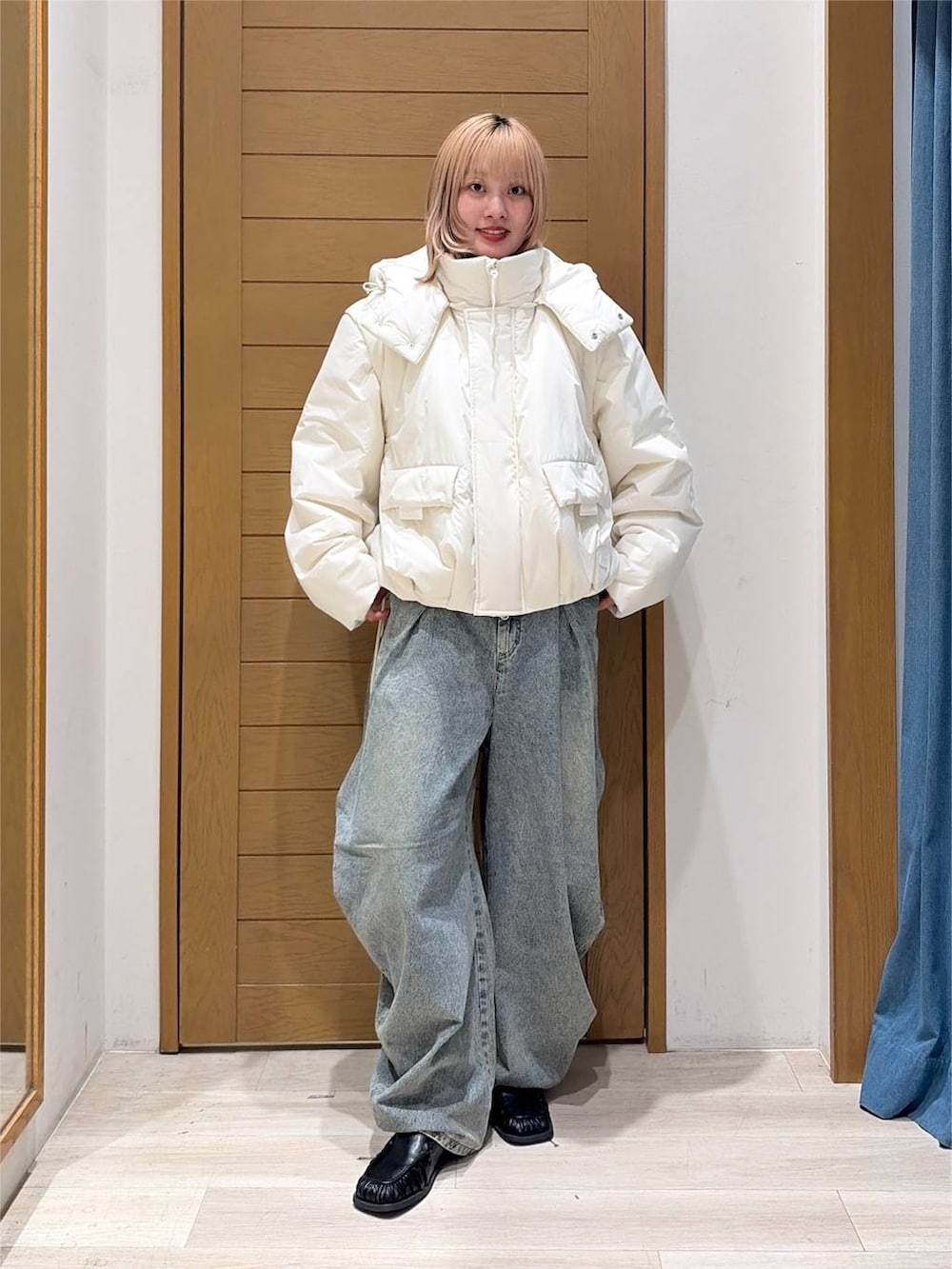 ブラック系のスリッポン、ブルー系のデニムパンツ、ホワイト系のブルゾンを着用したレディースの秋コーディネートの3枚目の写真