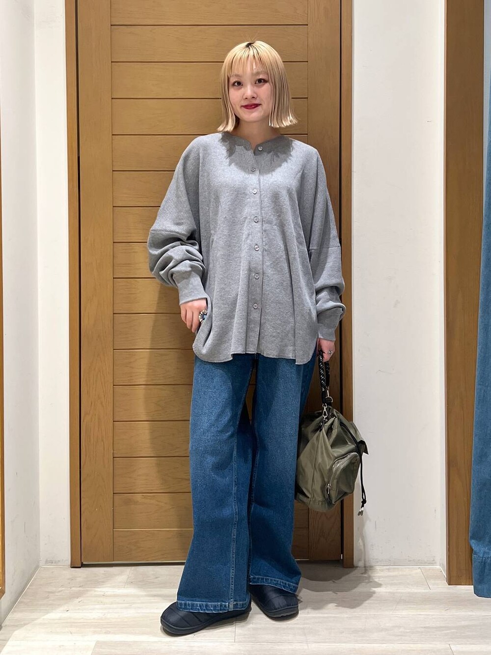 グリーン系のショルダーバッグ、グレー系のカーディガン/ボレロ、ブルー系のデニムパンツを着用したレディースの冬コーディネートの5枚目の写真