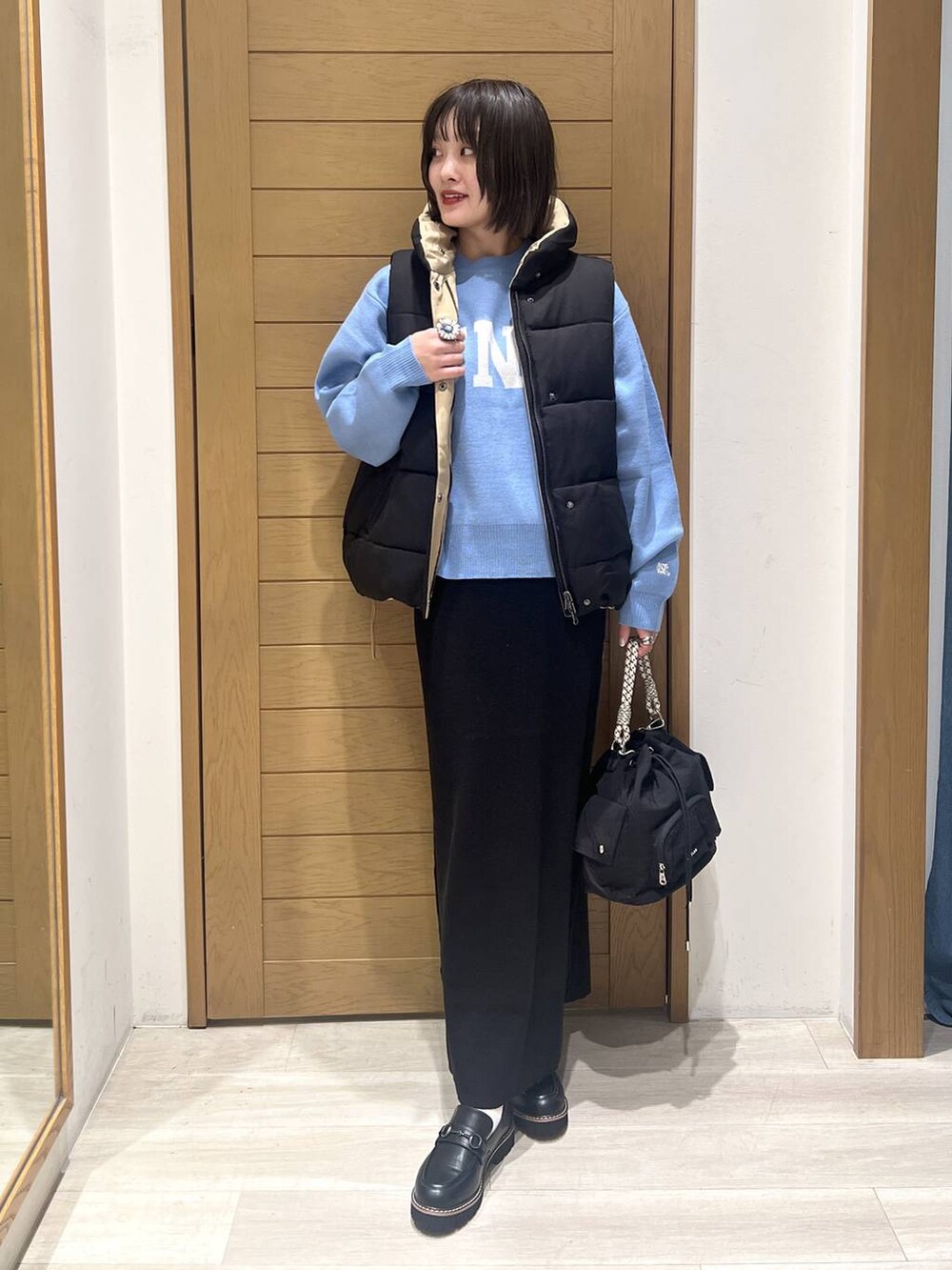 ブルー系のニット/セーター、ブラック系のローファー、ブラック系のハンドバッグを着用したレディースの秋コーディネートの2枚目の写真