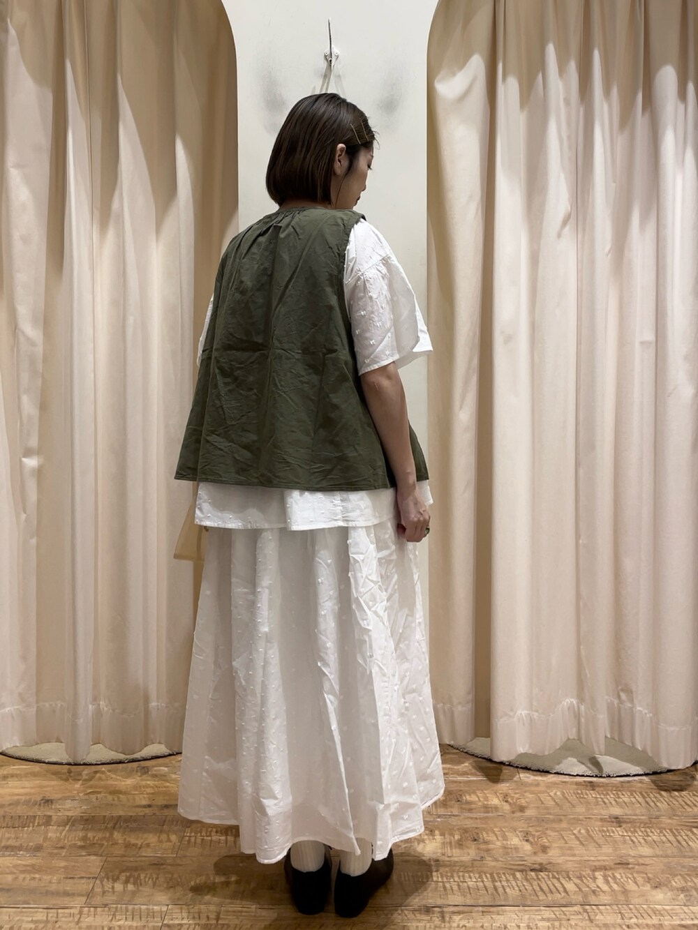 ベージュ系のハンドバッグ、ブラック系のその他シューズ、グリーン系のベストを着用したレディースの春コーディネートの3枚目の写真