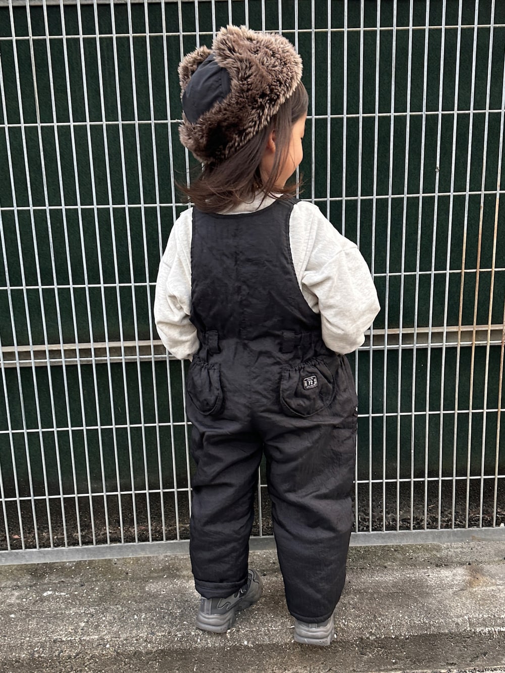 ブラック系のサロペット/オーバーオール、グレー系のスウェット、グレー系のスニーカーを着用したキッズの冬コーディネートの2枚目の写真
