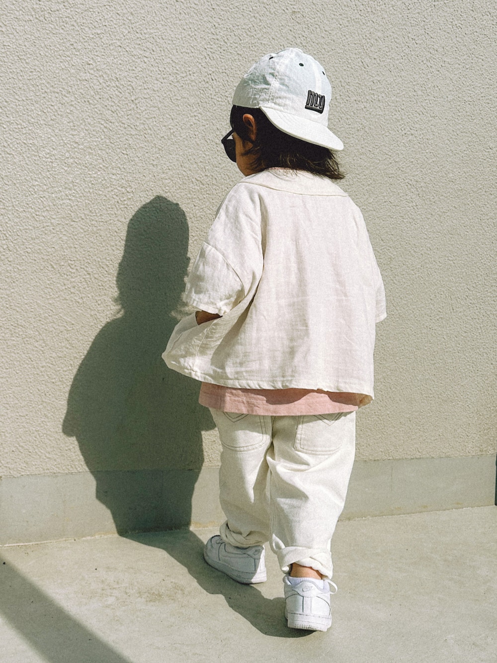 ホワイト系のデニムパンツ、ホワイト系のスニーカー、ホワイト系のシャツ/ブラウスを着用したキッズの春コーディネートの3枚目の写真