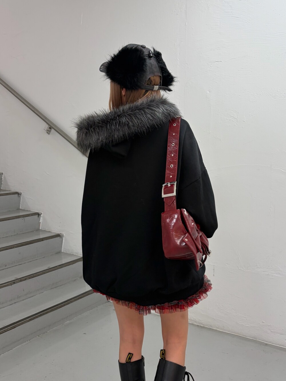 ブラック系のパーカー、レッド系のスカート、レッド系のショルダーバッグを着用したレディースの冬コーディネートの5枚目の写真