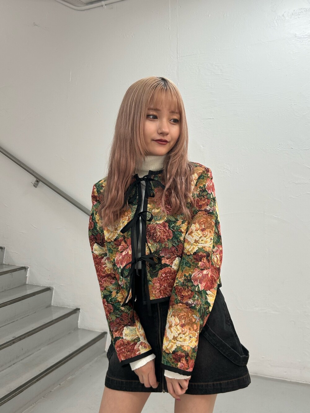 ブラック系のノーカラージャケット、ホワイト系のニット/セーター、ブラック系のデニムスカートを着用したレディースの冬コーディネートの4枚目の写真