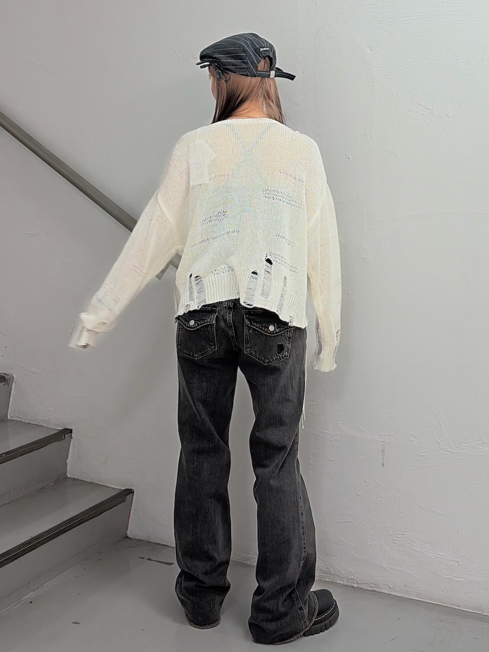 ホワイト系のニット/セーター、ブラック系のデニムパンツ、グレー系のハンチング/ベレー帽を着用したレディースの冬コーディネートの4枚目の写真