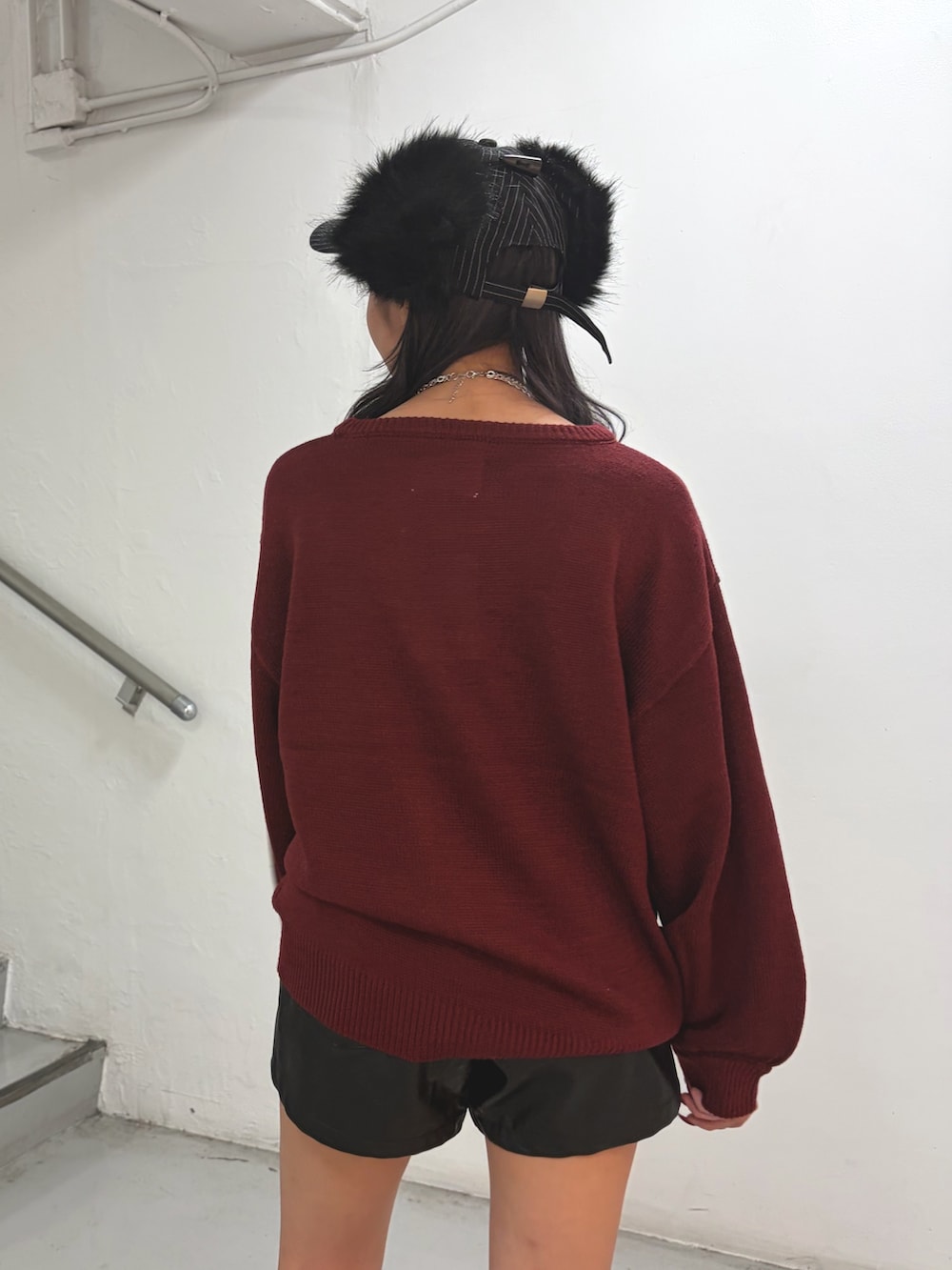 レッド系のニット/セーター、ブラック系のその他パンツ、ブラック系のキャップを着用したレディースの秋コーディネートの6枚目の写真