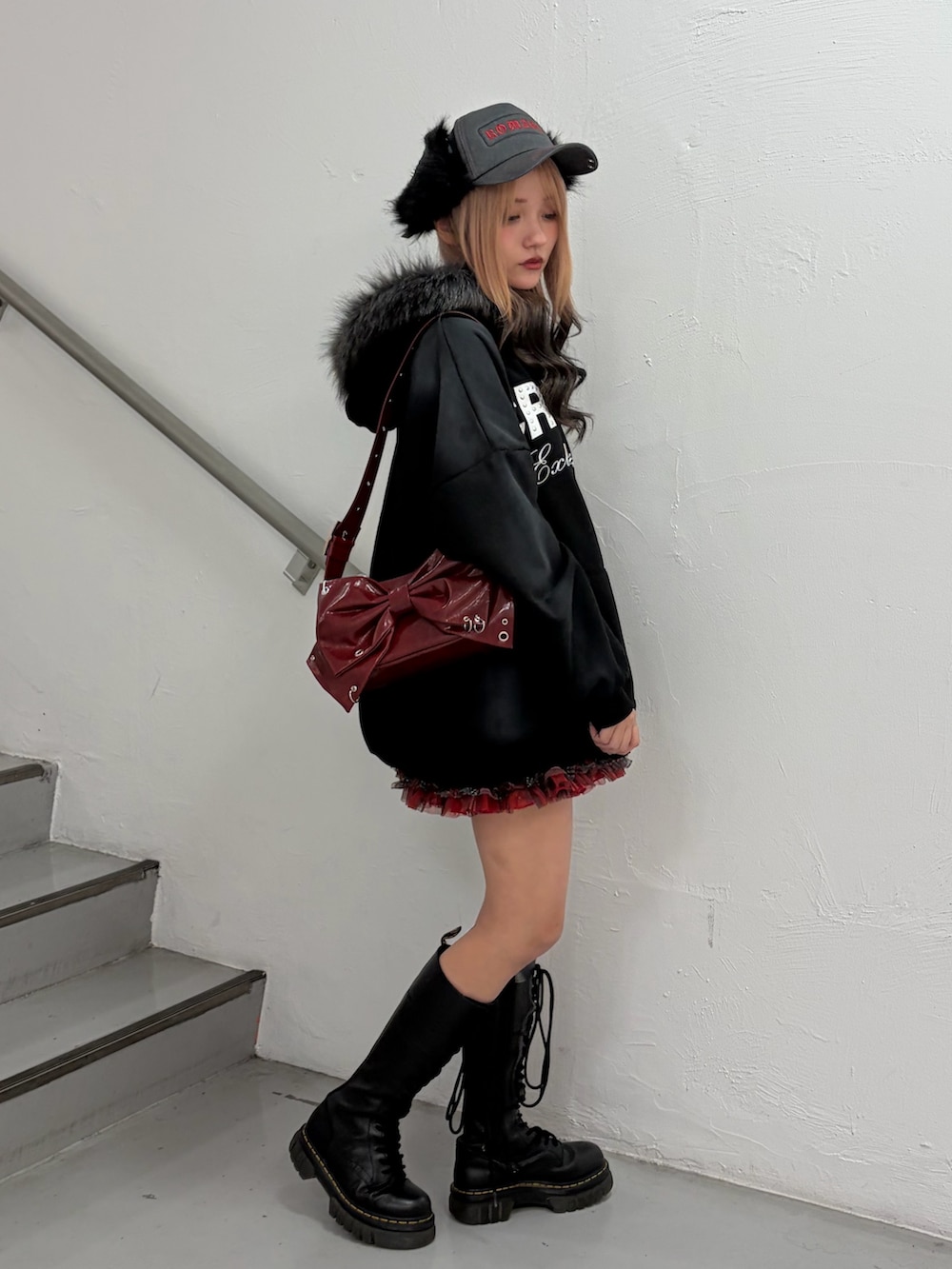 ブラック系のパーカー、レッド系のスカート、レッド系のショルダーバッグを着用したレディースの冬コーディネートの2枚目の写真