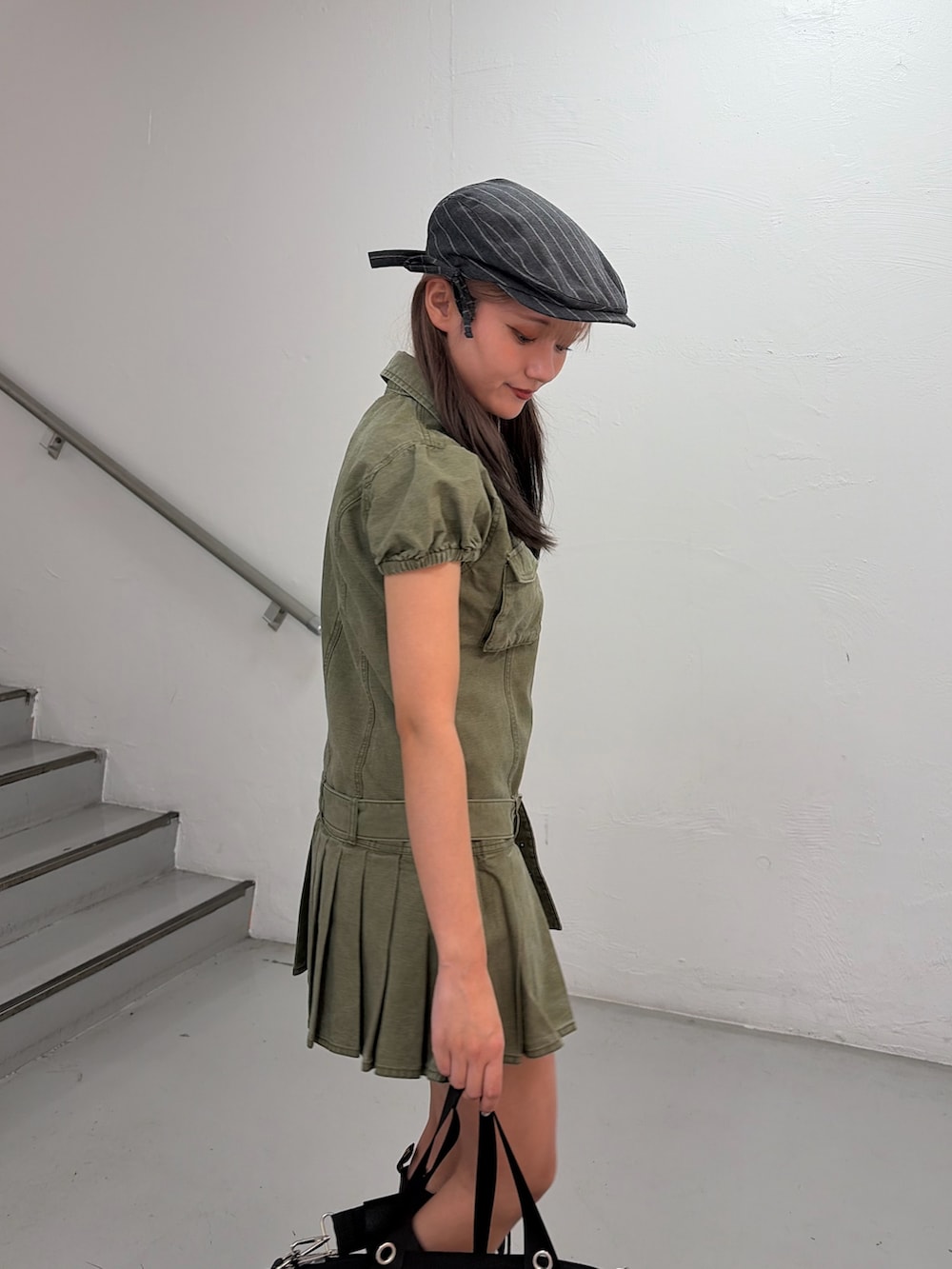 グリーン系のワンピース、ブラック系のボストンバッグ、グレー系のハンチング/ベレー帽を着用したレディースの冬コーディネートの5枚目の写真