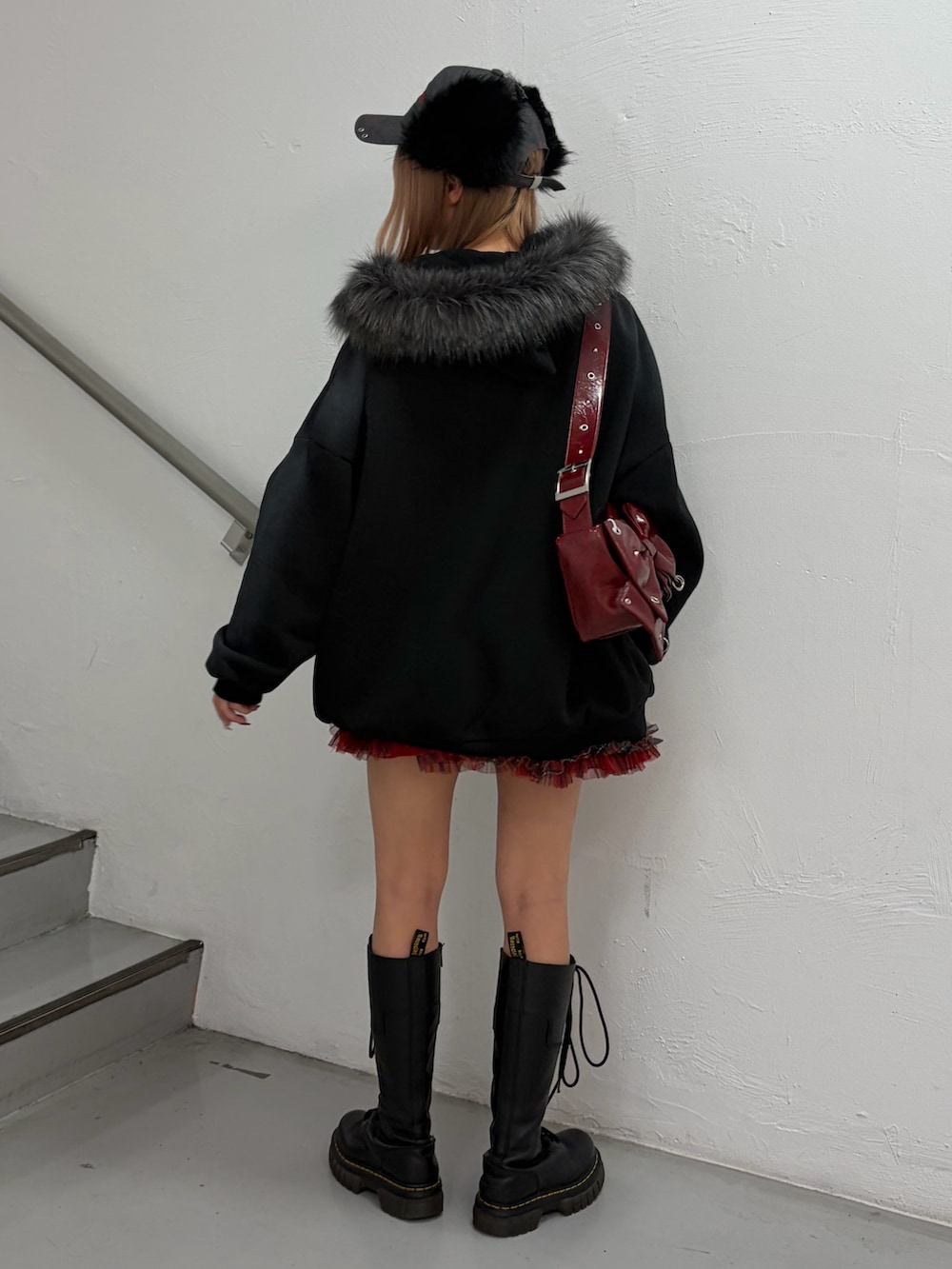 ブラック系のパーカー、レッド系のスカート、レッド系のショルダーバッグを着用したレディースの冬コーディネートの3枚目の写真