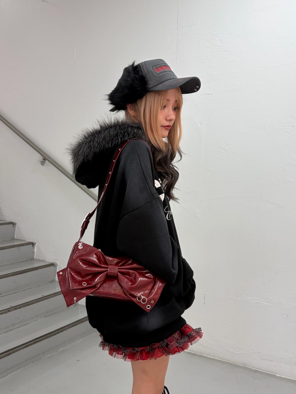 ブラック系のパーカー、レッド系のスカート、レッド系のショルダーバッグを着用したレディースの冬コーディネートの6枚目の写真