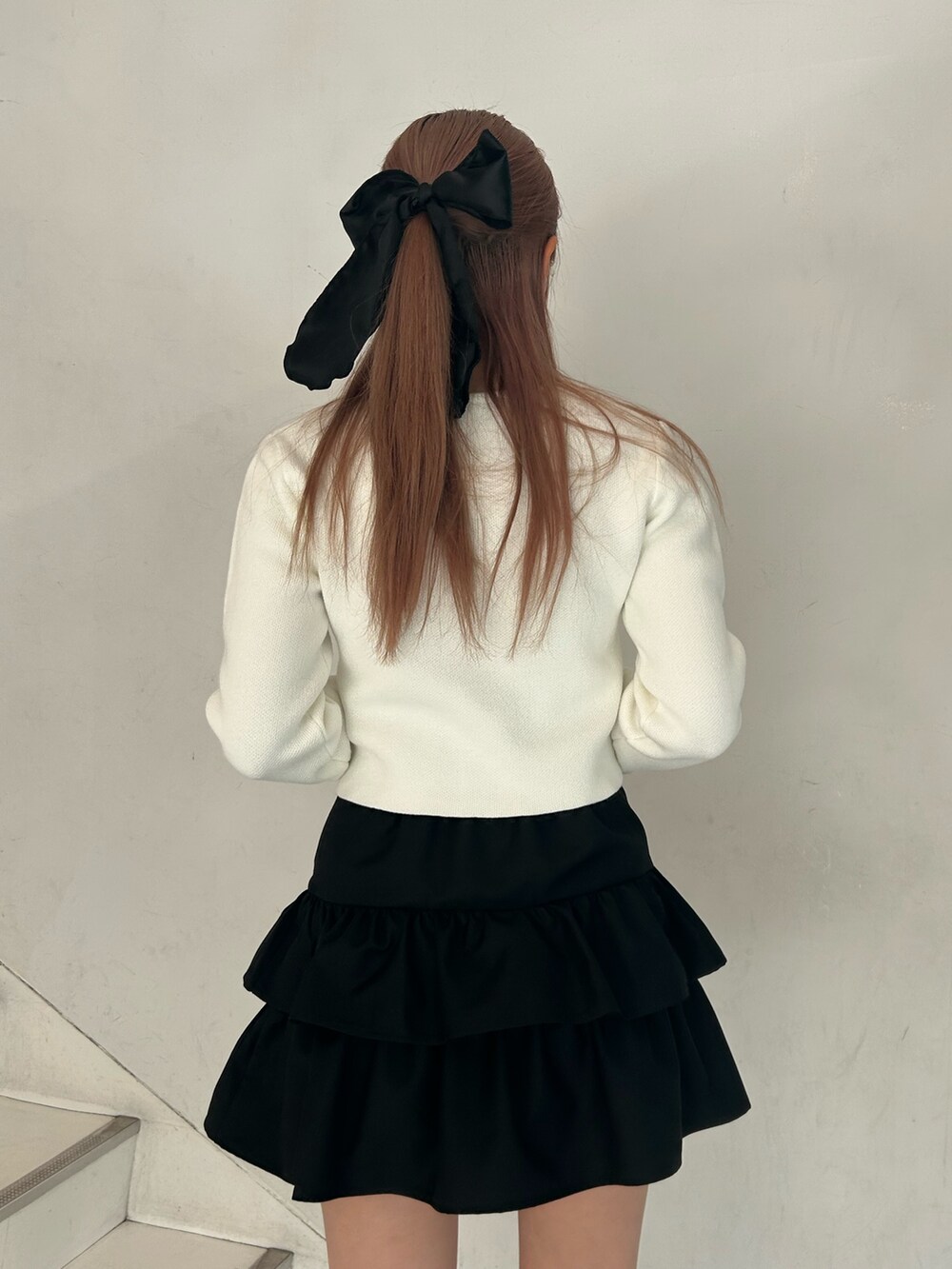 ホワイト系のカーディガン/ボレロ、ブラック系のスカート、ブラック系のブーツを着用したレディースの春コーディネートの6枚目の写真