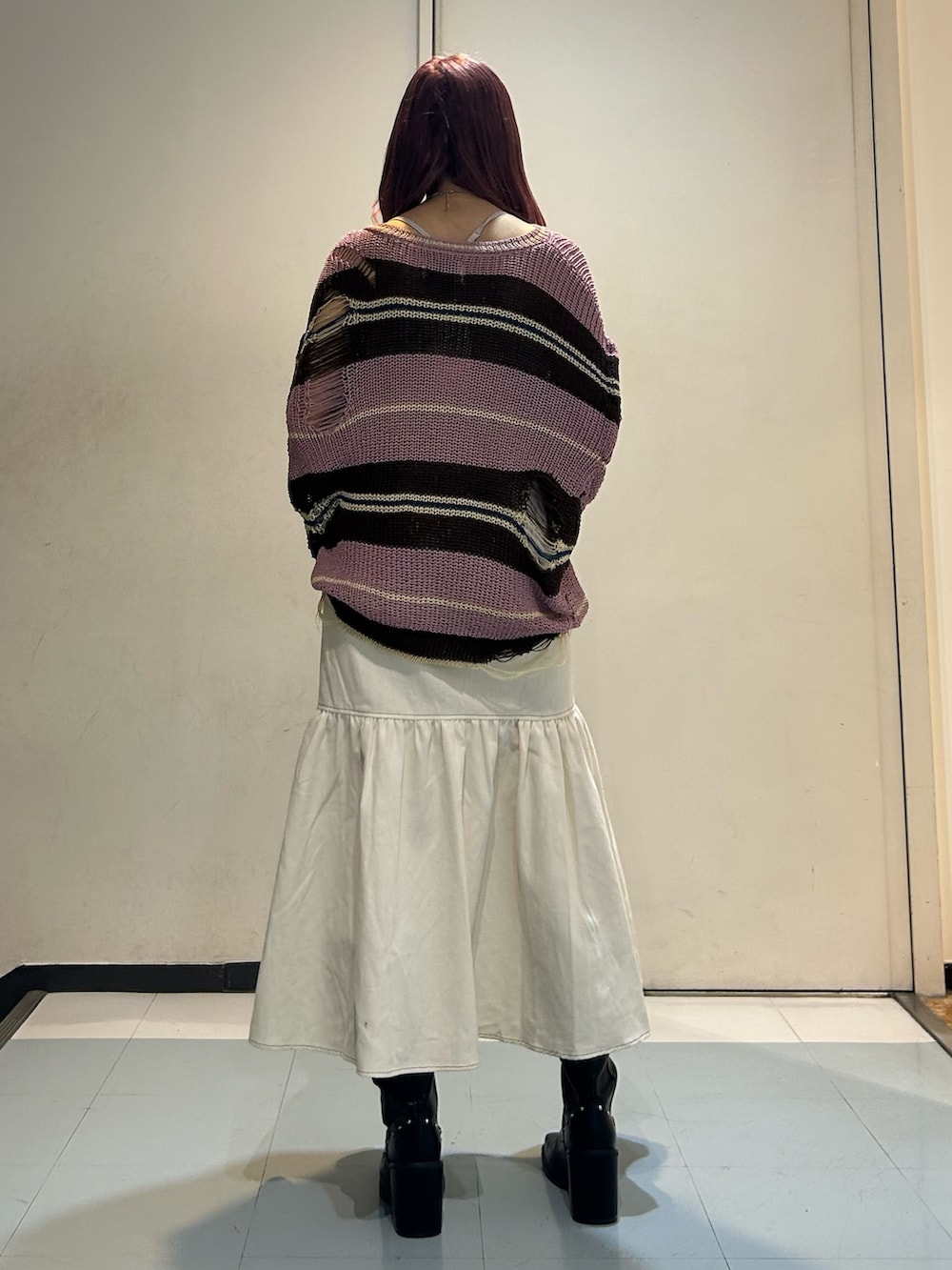 ピンク系のニット/セーター、ホワイト系のワンピース、ブラック系のブーツを着用したレディースの春コーディネートの2枚目の写真