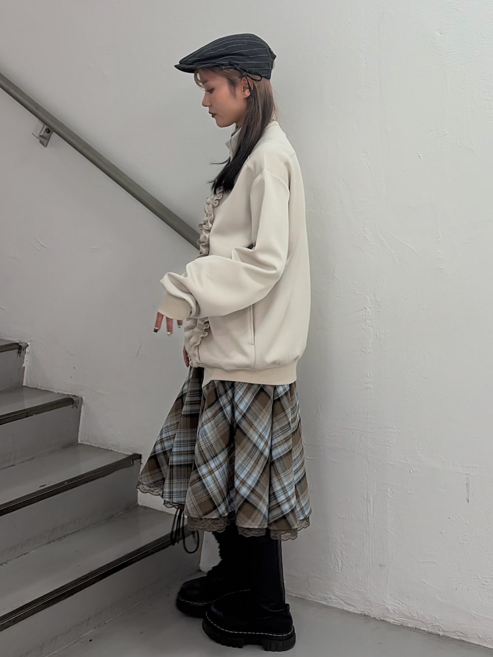 ホワイト系のジャージ、ブラウン系のスカート、グレー系のハンチング/ベレー帽を着用したレディースの冬コーディネートの2枚目の写真