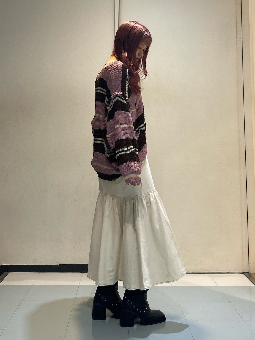 ピンク系のニット/セーター、ホワイト系のワンピース、ブラック系のブーツを着用したレディースの春コーディネートの3枚目の写真