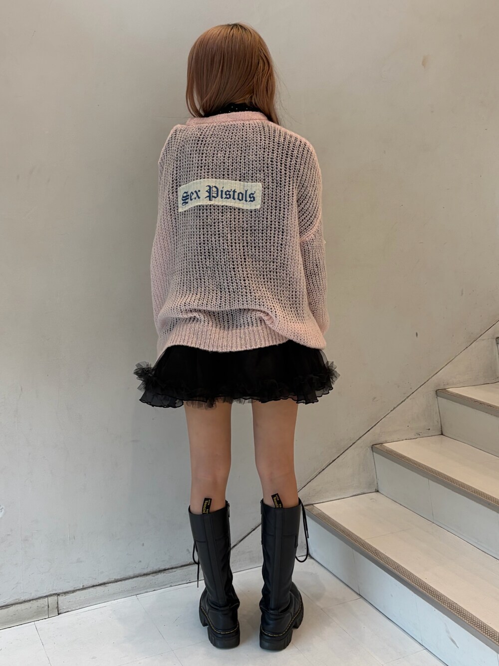 ピンク系のニット/セーター、ブラック系のスカート、ブラック系のシャツ/ブラウスを着用したレディースの秋コーディネートの4枚目の写真