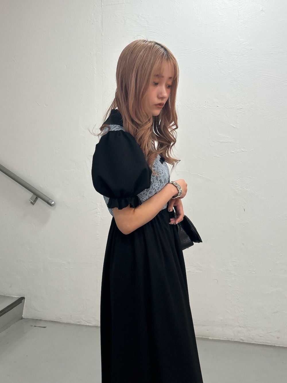 ブラック系のワンピース、ブラック系のハンドバッグ、シルバー系のブレスレットを着用したレディースの春コーディネートの5枚目の写真