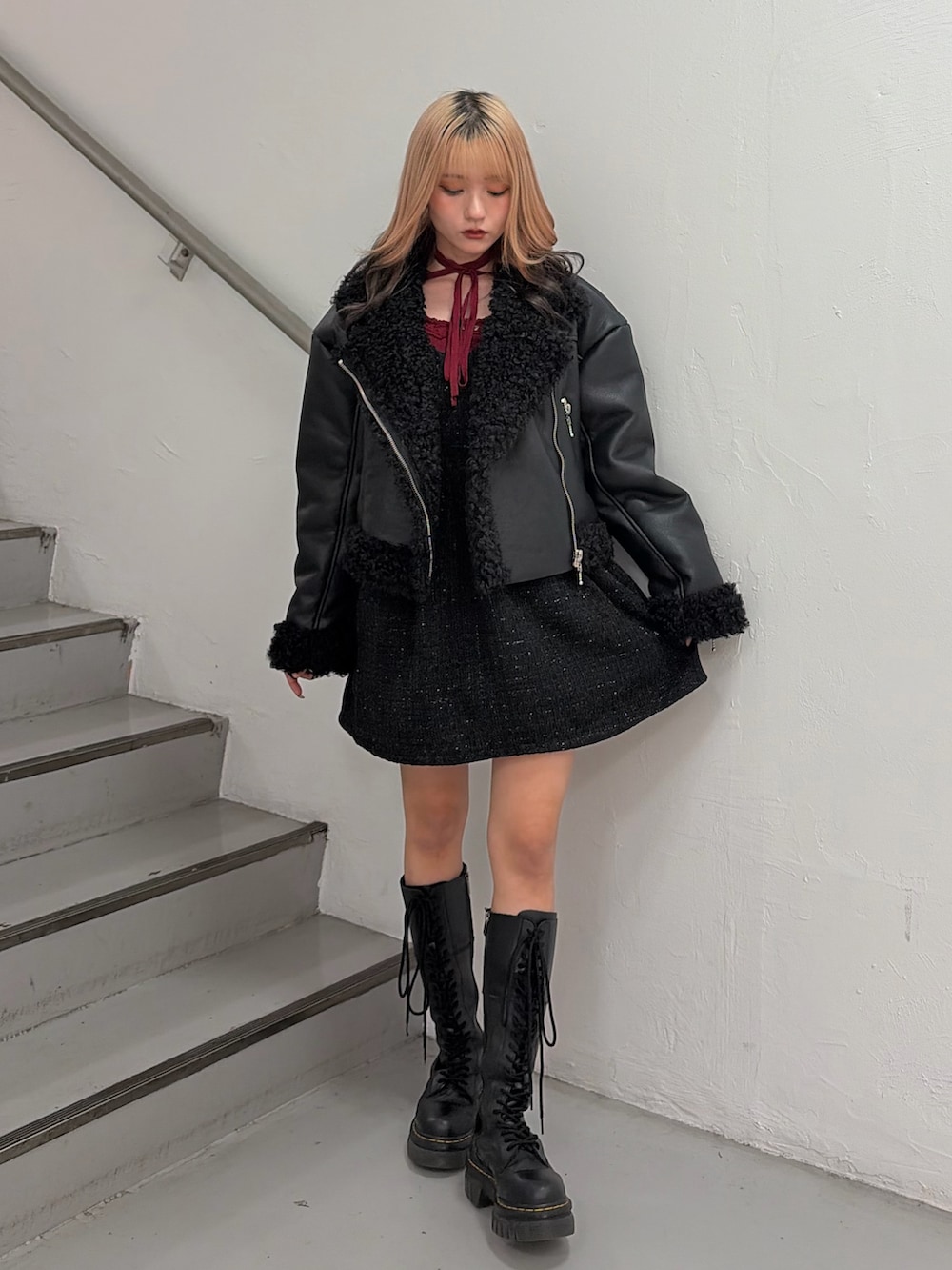 ブラック系のムートンコート、ブラック系のワンピース、レッド系のニット/セーターを着用したレディースの秋コーディネートの2枚目の写真