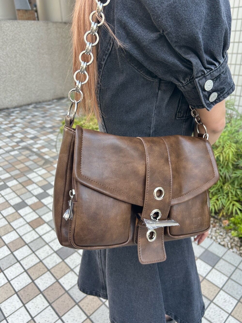 ブラック系のワンピース、ブラック系のブーツ、ブラウン系のハンドバッグを着用したレディースの春コーディネートの7枚目の写真